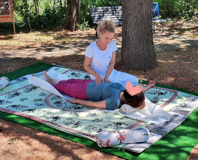 Behandlung des Abdomens mit Uke in Rückenlage auf einer Matte in der Nähe eines Baumes in einem öffentlichen Park