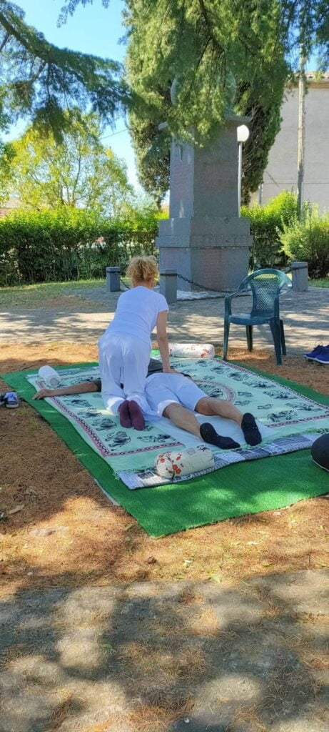 Tratamiento de espalda con ukè en decúbito prono sobre una colchoneta en un parque público