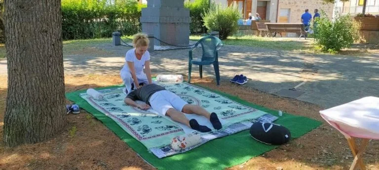 Shoulder treatment with uke prone on a mat near a tree in a public park