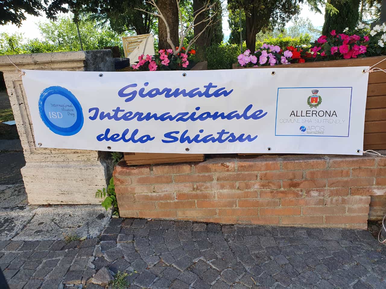 Sign with the inscription International Shiatsu Day posted at the entrance of a public park with the ISD logo and the patronage of the municipality of Allerona and Apos