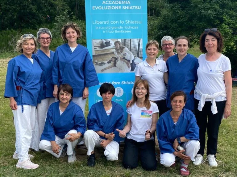 A group of women posing for a photo, near the panel of the Shiatsu evolution academy.